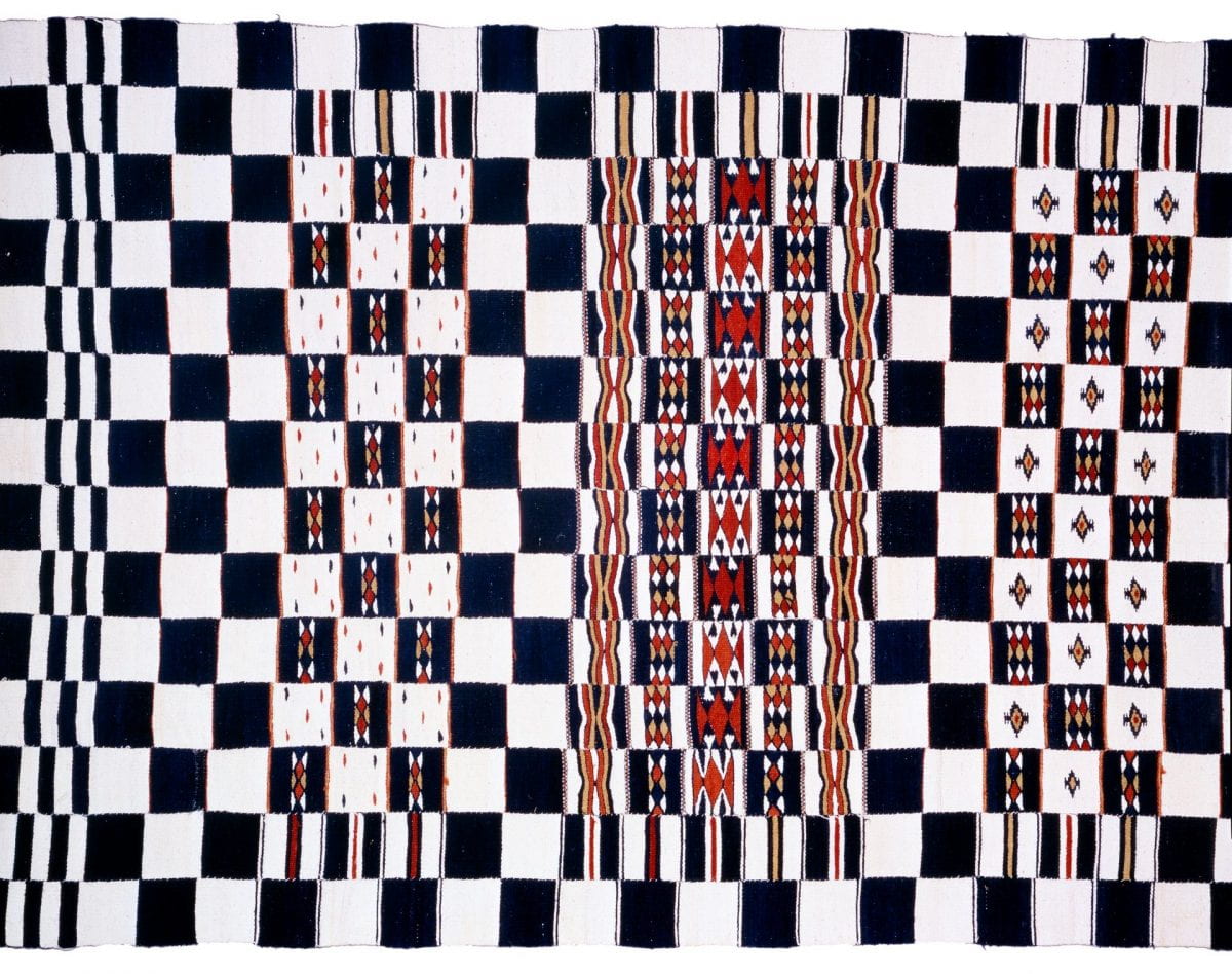 Black and white checkerboard patterned textile with sporadic designs in red