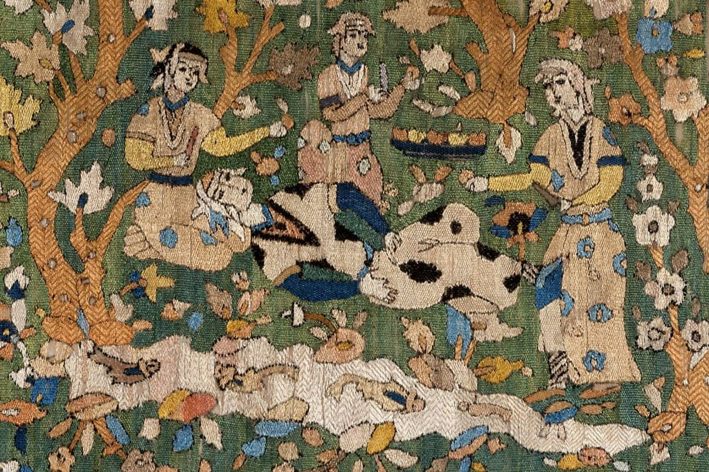 Detail of a textile showing three seated woman with a fourth at the center lying on her back above a pond full of fish