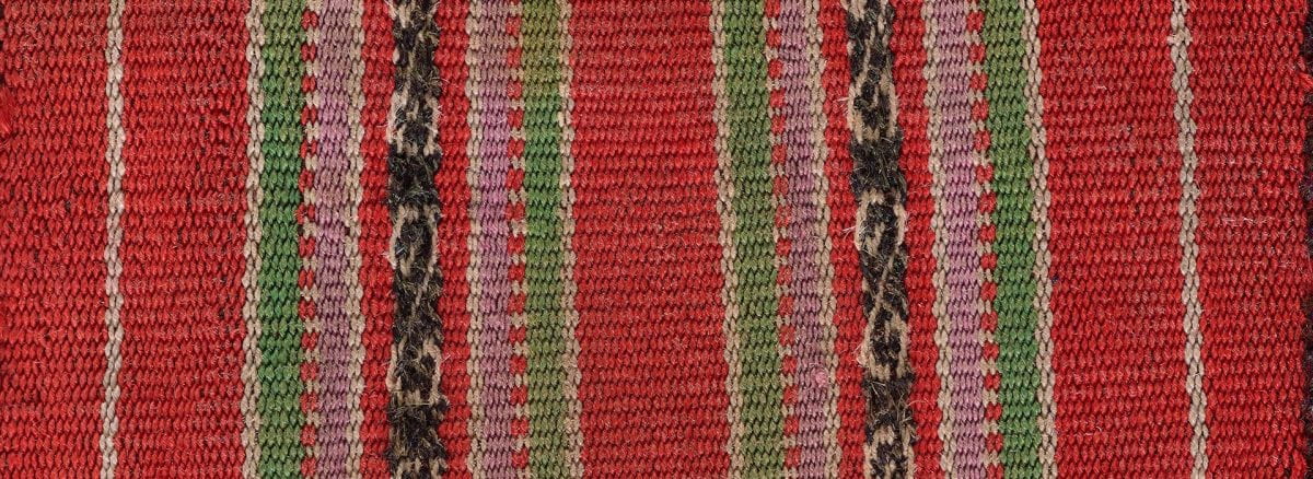 Detail of a woven textile with red, green, lavender and dark brown vertical stripes