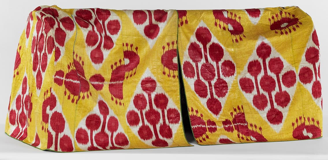 Yellow, tented textile with a vertical slit down the center and red and white patterning