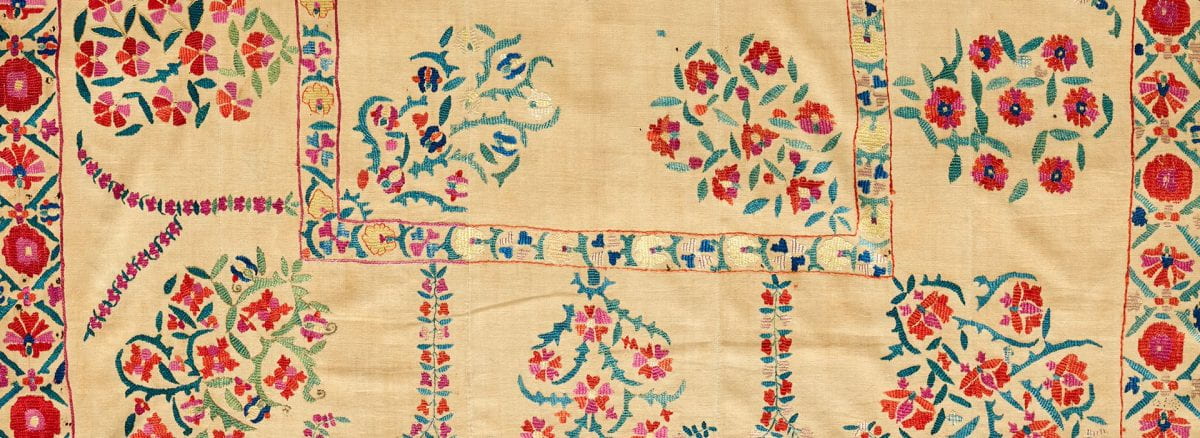 Detail of a textile with a cream background and sprays of embroidered flowers