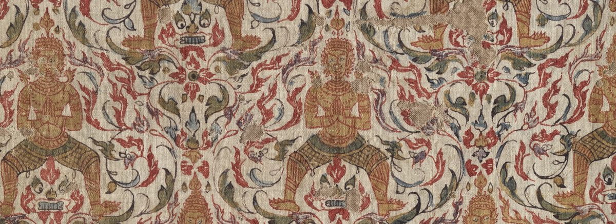 White textile fragment with red, gold, and green floral motifs and wide-stanced repeated figures.