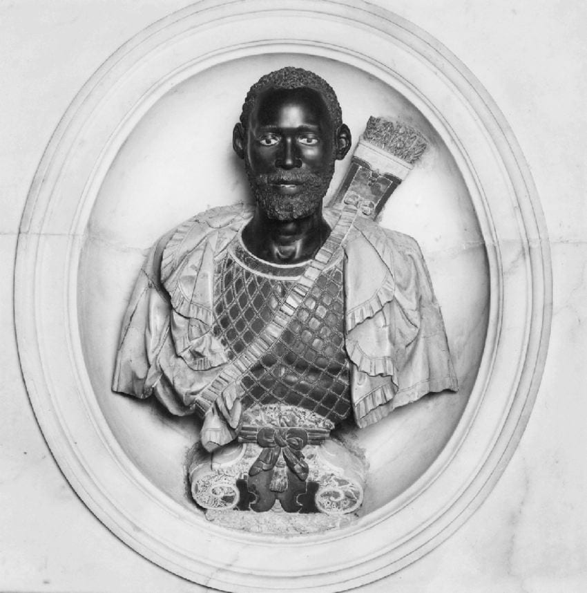 Black-and-white photograph showing a marble bust of a Black male dressed in a short cape with a sling of arrows worn across his chest