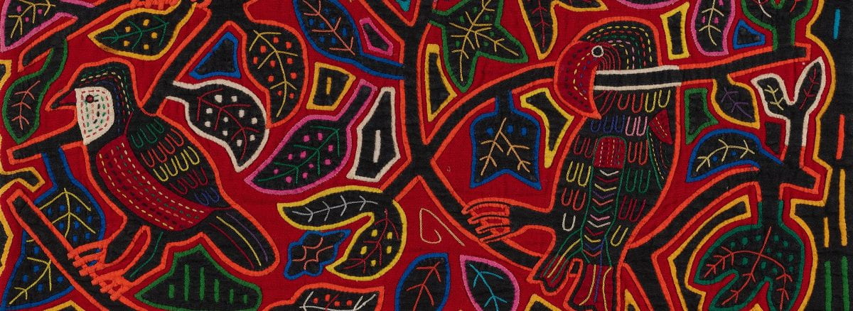 Colorful textile depicting leaves and a parrot on the right and another bird on the left in a reverse applique technique.